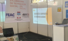 Imagem 1: Estande da FEAC no SINPETE, com o banner e mesa da Incubadora de Tecnologia Social