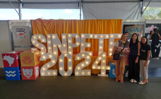 Imagem 3 A coordenadora da Incubadora de Tecnologia Social Ana Maria Rita Milani e as alunas e colaboradoras Priscila Nascimento e Laura Ferreira ao lado do letreiro do SINPETE 2024.